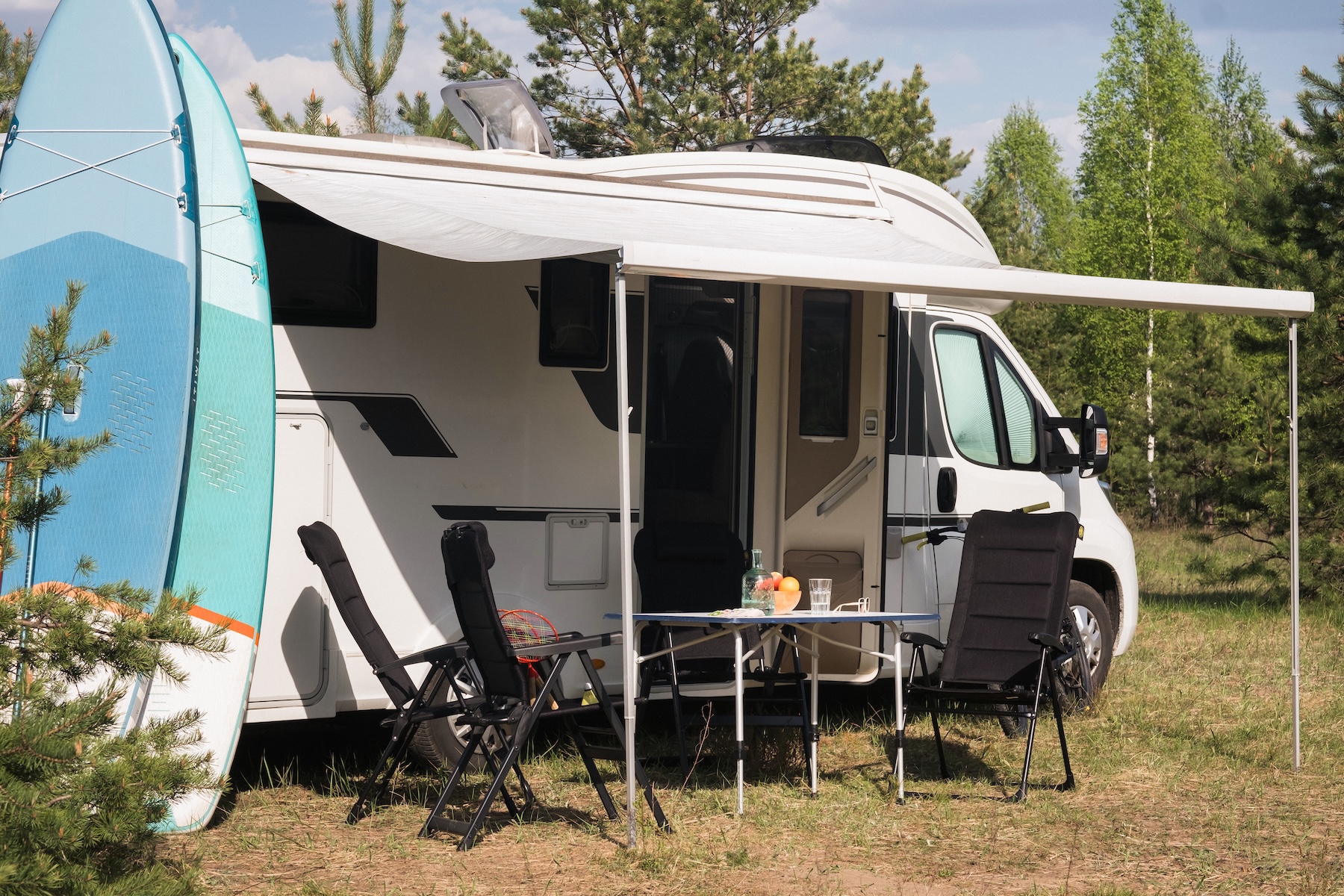 A recreational vehicle with paddle boards parked in a rural Australian setting